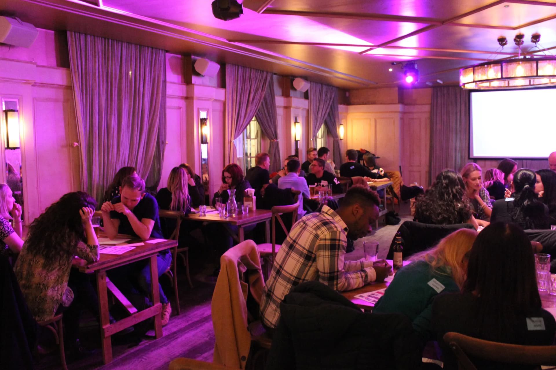 Busy quiz night, host at the screen and every table full.