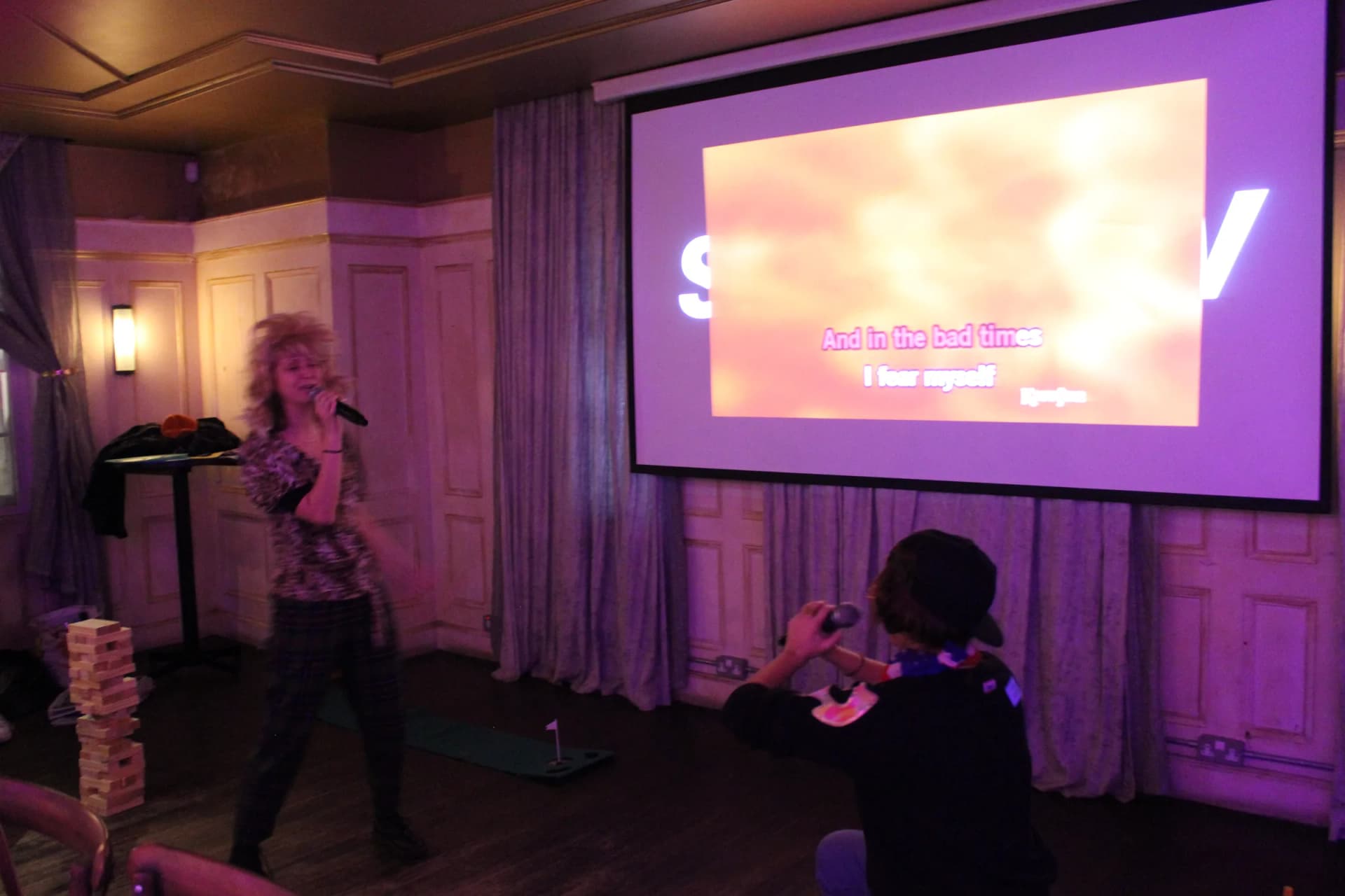 Guest belting out a karaoke number in front of the lyrics screen.