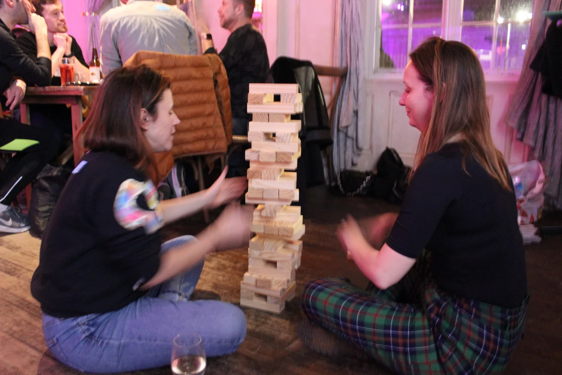 Two guests laughing over a tall giant Jenga tower.